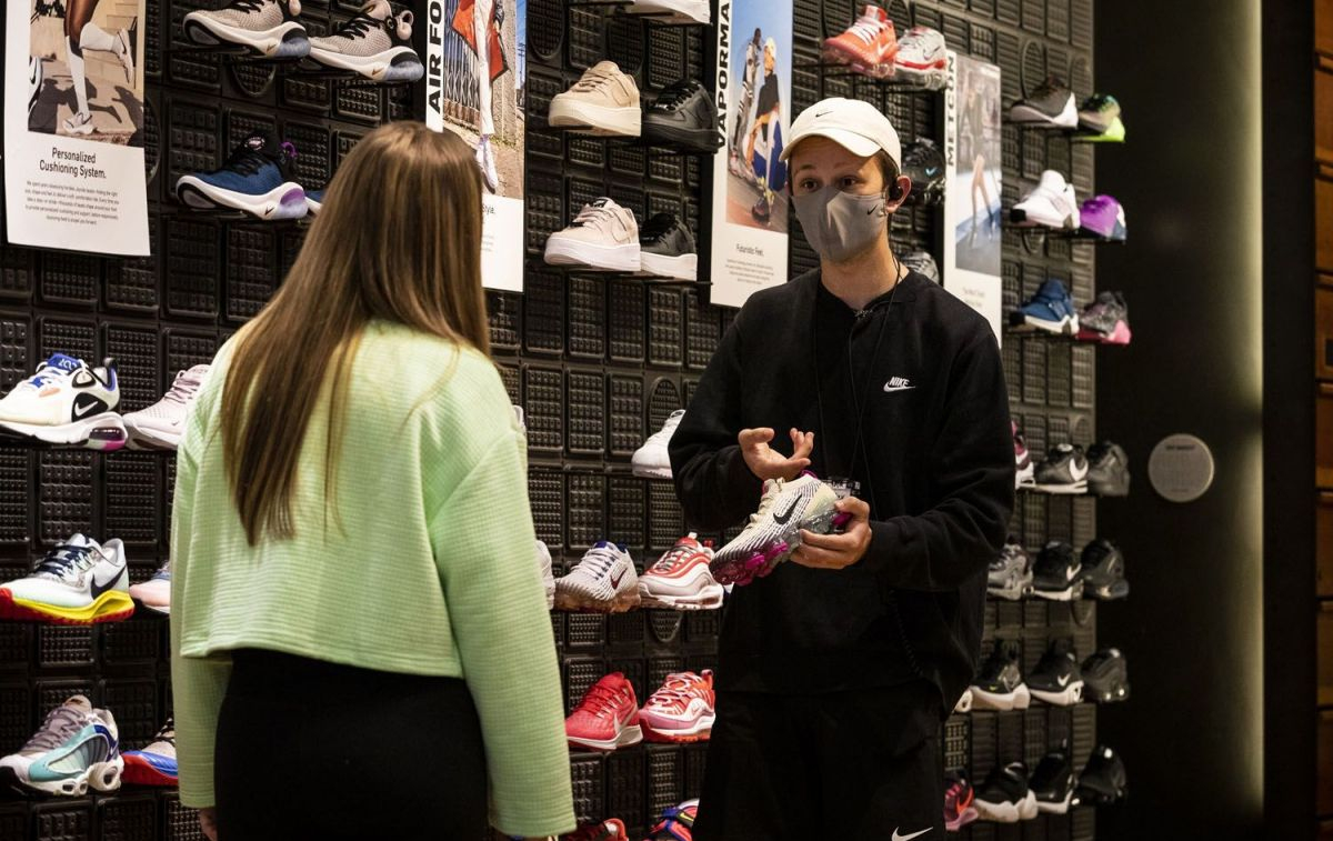 Una dependienta muestra unas zapatillas Nike en una tienda / EP