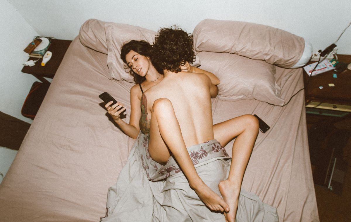 Una pareja que está en la cama y la chica algo distraída / PEXELS 